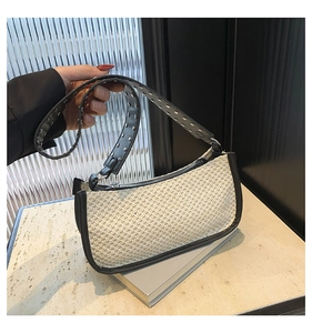 Detail of raffia woven shoulder bag with black leather strap and metal eyelet rivets