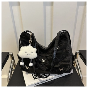 Detail of black pleated tote bag with silver butterfly accents and cloud charm