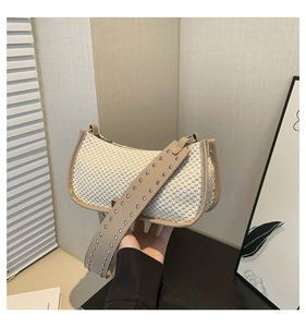 Detail of cream woven shoulder bag with wide leather strap and silver rivet studs