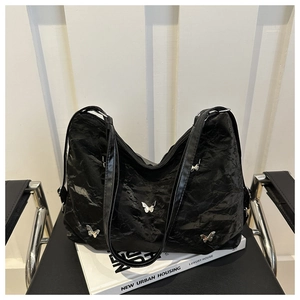 Detail of black wrinkled hobo bag featuring silver butterfly studs and spacious design