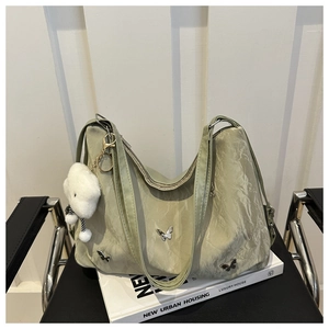Detail of light green ruched bag with silver butterfly buckle and plush charm