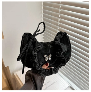 Detail of black velvet shoulder bag with ruffled edges and silver butterfly buckle