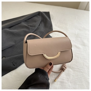 Nahaufnahme der beigen Baguette-Tasche mit goldener Schnalle und Knotengurt-Detail