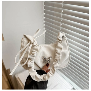 Close-up of white ruffle underarm bag featuring a metallic silver butterfly clasp detail