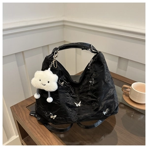 Detail of black pleated hobo bag with silver butterfly charms and cloud plush pendant