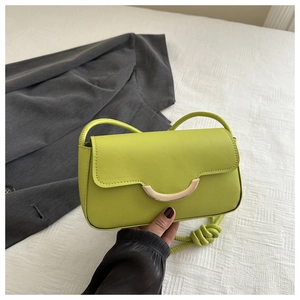 Detail der neongrünen Leder-Baguette-Tasche mit Goldbuckle und geflochtenem Gurt