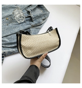 Close-up of beige woven texture with black trim and silver zipper on a chic shoulder bag