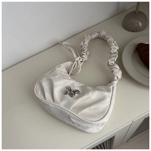 Close-up of beige underarm bag with marble texture, silver butterfly buckle and scrunchie handle