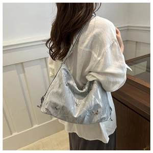 Detail of silver metallic tote bag featuring butterfly accents and pleated soft texture