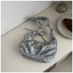 Silver pleated underarm bag featuring a metallic butterfly ornament and ruffled strap
