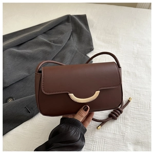 Detailansicht der braunen Baguette-Tasche aus mattem Leder mit goldener Schnalle und Knotengurt