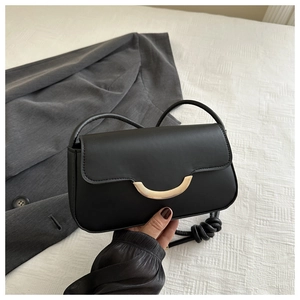 Nahaufnahme einer schwarzen Ledertasche mit goldener Mondsichel-Schnalle und Knotengurt