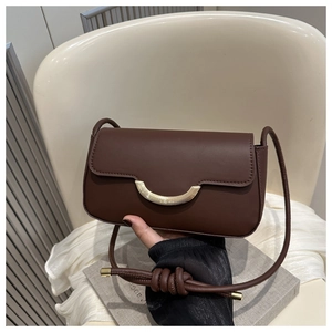 Detail shot of a dark brown baguette bag with a semi-moon golden metal buckle and leather texture
