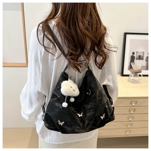 Large black pleated tote bag with silver butterfly charms and white plush cloud pendant
