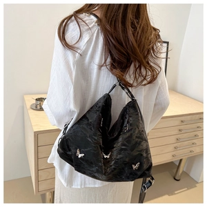 Detail of black pleated hobo bag with silver butterfly buckles and soft texture finish