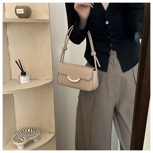 Detail der beigen Baguette-Tasche mit goldenem Mondsichelverschluss und Seilträger