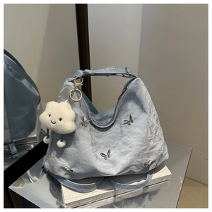 Detail of light blue pleated tote bag with silver butterfly charms and cloud pendant