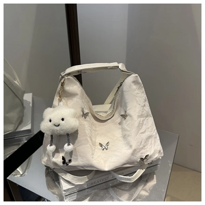 Detail of cream white pleated tote bag with silver butterfly charms and plush pendant