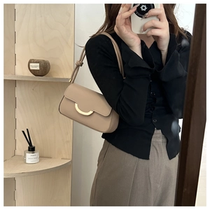 Detail of beige minimalist underarm bag with signature gold crescent moon metal buckle