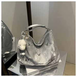 Close-up of silver pleated Hobo bag featuring butterfly metal patches and plush cloud charm