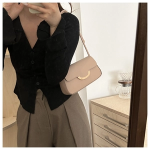 Mirror selfie showing a beige leather crossbody bag with a gold half-moon buckle detail