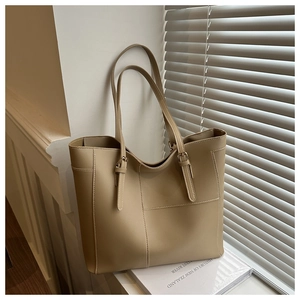 Detail of khaki tote bag showing adjustable straps with metal buckles and vertical stitching
