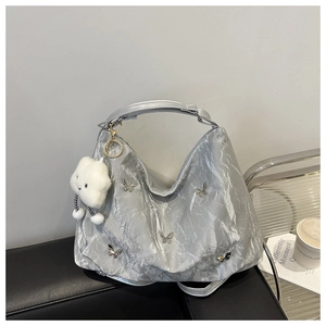 Detail of silver crescent tote bag featuring metallic texture and butterfly charms