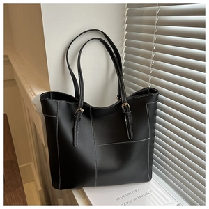 Close-up of black tote bag with white contrast stitching and gold buckle hardware