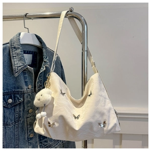 Detail of cream pleated tote bag with silver butterfly charms and fluffy cloud pendant