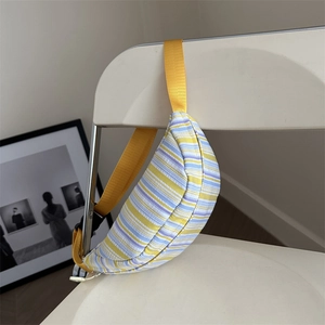 Colorful striped crossbody chest bag with yellow strap on white chair for casual summer style