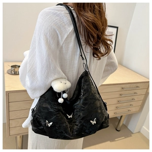 Detail of black pleated hobo bag with silver butterfly charms and plush white cloud charm