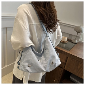 Vue détaillée d'un sac à bandoulière plissé bleu clair avec breloques papillon en argent