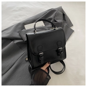 Detail eines schwarzen Vintage-PU-Lederrucksacks mit silbernen Schnallen auf grauem Blazer