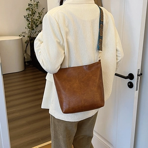 Vintage brown leather tote bag with ethnic style wide shoulder strap shown on model
