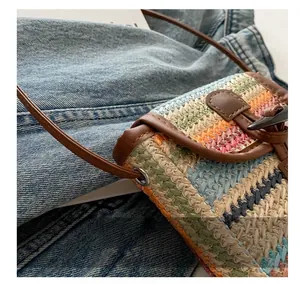 Close-up of colorful woven straw crossbody bag with brown leather trim and slim strap