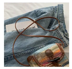 Detail showing the woven texture, leather strap, and horn button of the striped phone bag