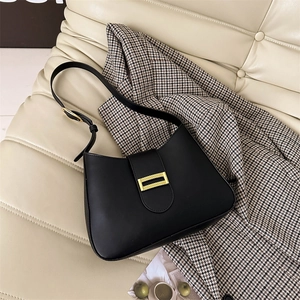 Minimalist black faux leather baguette bag with a gold buckle on an underarm shoulder bag