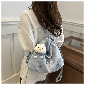 Détail du sac hobo bleu clair avec breloques papillon et pendentif nuage en peluche