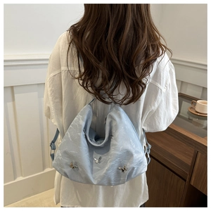 Détail du sac bleu clair avec décorations de papillons et texture de tissu plissé