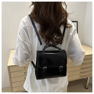 Nahaufnahme eines schwarzen PU-Lederrucksacks mit silbernen Schnallen am Modell