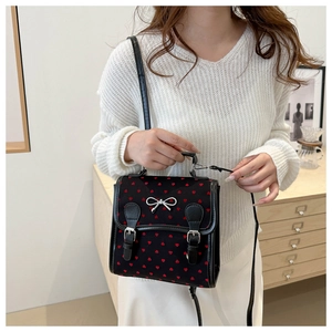 Detail of black canvas mini bag with red heart print and silver bow metal buckle