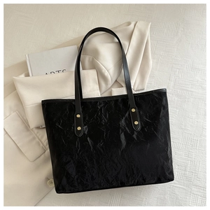 Detail of a black large tote bag with gold rivets and vintage wrinkled texture