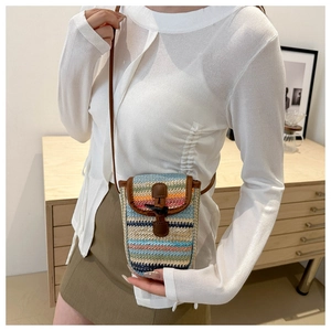 Close-up of bohemian rainbow woven straw phone bag with leather trim and wood toggle