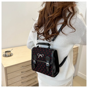 Lifestyle view of casual black canvas backpack with red heart prints and silver bow buckle