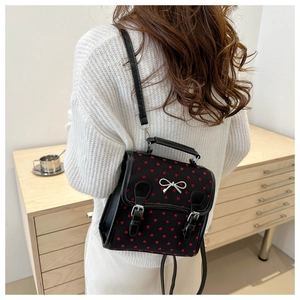 Detail of a mini black heart print backpack with a silver bow and leather straps