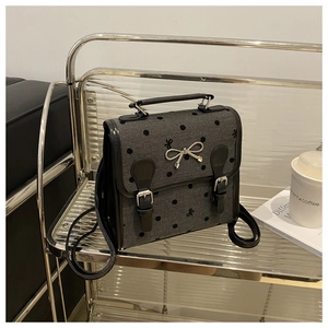 Detail of retro polka dot backpack with silver bow charm and black leather straps