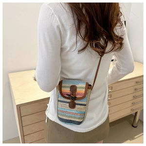 Macro shot of bohemian woven phone bag with multi-color stripes and horn button detail