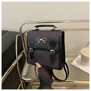 Detail of mini black backpack with red heart prints and silver bow buckle handheld