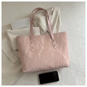 Close-up of pink tote bag with crinkled patent finish and golden rivet details