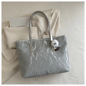 Silver tote bag with crinkled metallic texture and plush monster charm detail